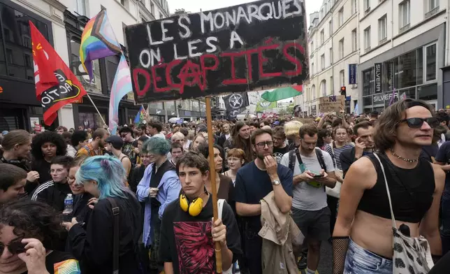 A demonstrator holds a poster which reads 'the monarchs were beheaded' during a protest, responding to a call from the far-left party who criticized as a power grab the president's appointment of a conservative new prime minister, Michel Barnier, in Paris, France, Saturday, Sept. 7, 2024. (AP Photo/Michel Euler)