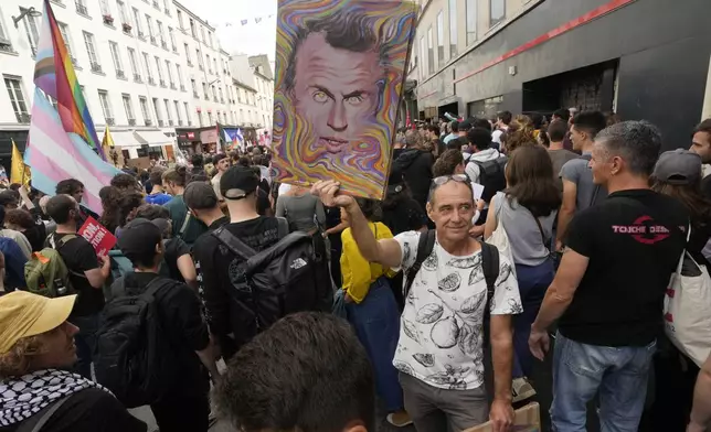 A demonstrator holds a poster featuring French President Emmanuel Macron during a protest, responding to a call from the far-left party who criticized as a power grab the president's appointment of a conservative new prime minister, Michel Barnier, in Paris, France, Saturday, Sept. 7, 2024. (AP Photo/Michel Euler)