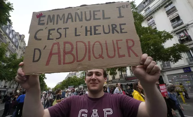 A demonstrator holds a placard which reads 'Emmanuel it's time to abdicate' during a protest, responding to a call from the far-left party who criticized as a power grab the president's appointment of a conservative new prime minister, Michel Barnier, in Paris, France, Saturday, Sept. 7, 2024. (AP Photo/Michel Euler)