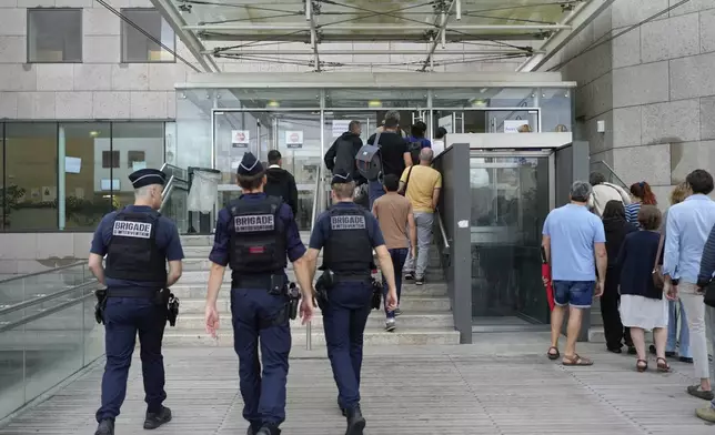 FILE - Police officers walk in the Avignon court house prior to the trial of Dominique Pelicot, in Avignon, southern France, Thursday, Sept. 5, 2024. (AP Photo/Lewis Joly, File)