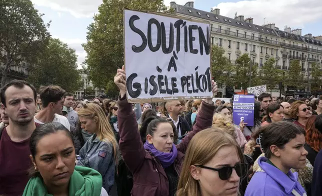 People take part in a gathering in support of 71-year-old Gisele Pelicot who was allegedly drugged by her ex-husband and raped by dozens of men while unconscious, Saturday, Sept. 14, 2024 in Paris. Placard reads, "support for Gisle Pelicot." (AP Photo/Michel Euler)