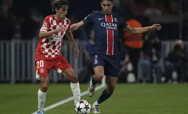 Girona's Bryan Gil, left, and PSG's Achraf Hakimi fight for the ball during the Champions League opening phase soccer match between Paris Saint-Germain and Girona at the Parc des Princes stadium in Paris, France, Wednesday, Sept. 18, 2024. (AP Photo/Christophe Ena)