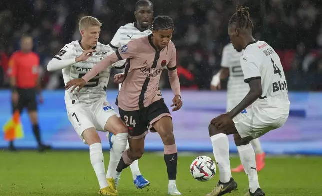 PSG's Senny Mayulu, center, duels for the ball with Rennes' Albert Gronbaek, left, and Rennes' Christopher Wooh during the French League One soccer match between Paris Saint-Germain and Rennes at the Parc des Princes in Paris, Friday, Sept. 27, 2024. (AP Photo/Thibault Camus)