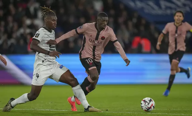 PSG's Ousmane Dembele, center, duels for the ball with Rennes' Christopher Wooh during the French League One soccer match between Paris Saint-Germain and Rennes at the Parc des Princes in Paris, Friday, Sept. 27, 2024. (AP Photo/Thibault Camus)