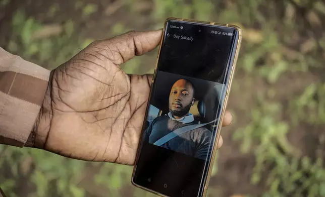 Moustapha Sabally displays a photo of his son who is a doctor in America on his mobile phone in the village of Kwinella, Gambia, on July 27, 2024. ( AP Photo/Annika Hammerschlag)