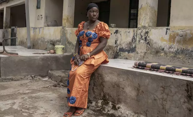 Binta Bah, whose husband Suleyman works in a factory in Germany, poses for a portrait outside her house in the village of Kwinella, Gambia, on July 27, 2024. (AP Photo/Annika Hammerschlag)