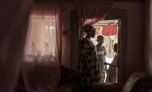 Musukebbe Manjang, left, speaks with her son Boubacar Darbo, center, and his sister Fatima in the village of Kwinella, Gambia, on July 27, 2024. (AP Photo/Annika Hammerschlag)