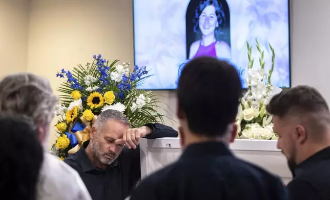 Dorin Irimie, husband of Ana Cristina Irimie, a math teacher killed during a shooting at Apalachee High School, mourns by her casket at her funeral service at Hamilton Mill Memorial Chapel and Gardens in Buford, Ga., on Saturday, Sept. 14, 2024. (Arvin Temkar/Atlanta Journal-Constitution via AP)