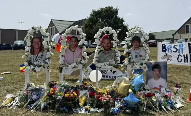 A poster with images of shooting victims from left, Cristina Irimie, Mason Schermerhorn, Richard Aspinwall and Christian Angulo is displayed at a memorial outside Apalachee High School, Tuesday, Sept. 10, 2024, in Winder, Ga. (AP Photo/Charlotte Kramon)