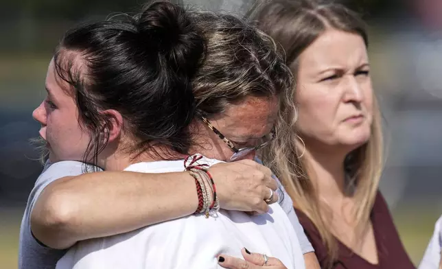 People embrace at a makeshift memorial after a shooting Wednesday at Apalachee High School, Thursday, Sept. 5, 2024, in Winder, Ga. (AP Photo/Mike Stewart)