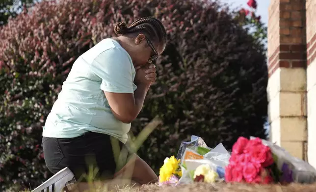 Linda Carter, of Grayson, Ga., kneels near Apalachee High School to place flowers as she mourns for the slain students and teachers on Thursday, Sept. 5, 2024, in Winder, Ga. (AP Photo/Brynn Anderson)