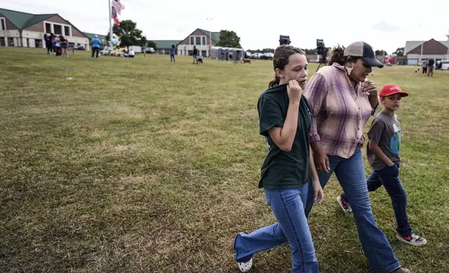 A family leaves a memorial where the American and state of Georgia flags fly half-staff after a shooting Wednesday at Apalachee High School, Thursday, Sept. 5, 2024, in Winder, Ga. (AP Photo/Mike Stewart)