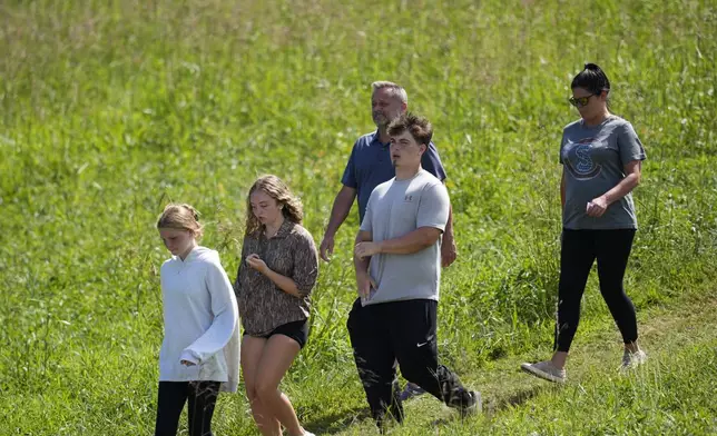 Students and parents walk off campus at Apalachee High School, Wednesday, Sept. 4, 2024, in Winder, Ga. (AP Photo/Mike Stewart)