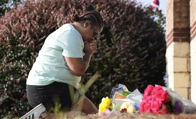 Linda Carter, of Grayson, Ga., kneels near Apalachee High School to place flowers as she mourns for the slain students and teachers on Thursday, Sept. 5, 2024, in Winder, Ga. (AP Photo/Brynn Anderson)