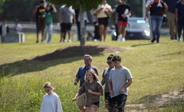 Students and parents walk off campus at Apalachee High School, Wednesday, Sept. 4, 2024, in Winder, Ga. (AP Photo/Mike Stewart)