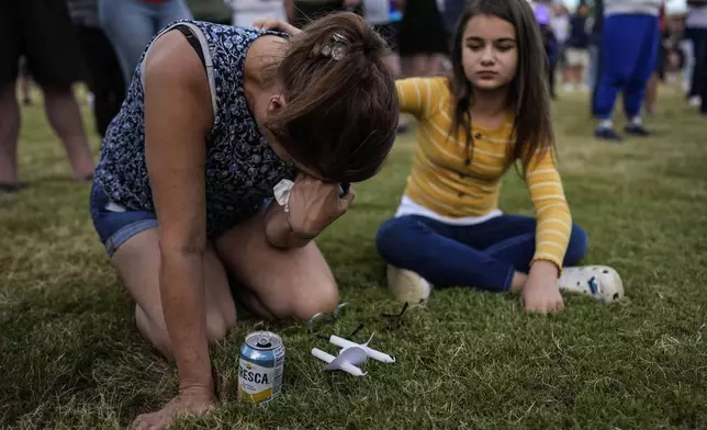 Brandy Rickaba and her daughter Emilie pray during a candlelight vigil for the slain students and teachers at Apalachee High School, Wednesday, Sept. 4, 2024, in Winder, Ga. (AP Photo/Mike Stewart)