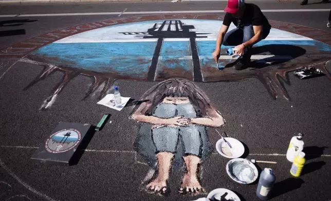 A man works on a painting as he takes part in a Global Climate Strike protest of the Fridays For Future movement near the chancellery in Berlin, Germany, Friday, Sept. 20, 2024. (AP Photo/Markus Schreiber)