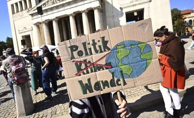 A demonstrator holds a placard reading "Politics - Climate - Change" during a Fridays for Future protest in Munich, Germany, Friday Sept. 20, 2024. (Felix Hörhager/dpa via AP)