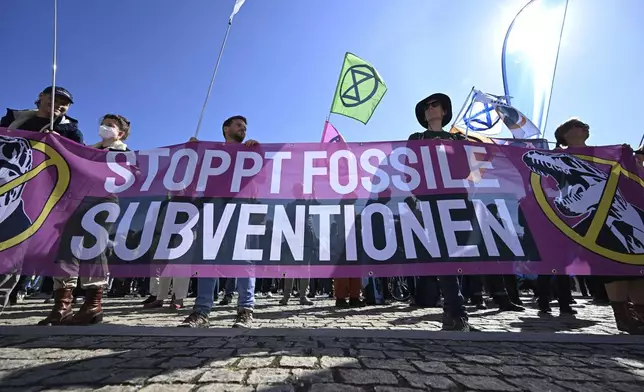 Demonstrators walk across Munich's Königsplatz with a placard reading "Stop fossil subsidies" during Fridays for Future protest in Munich, Germany, Friday Sept. 20, 2024. (Felix Hörhager/dpa via AP)