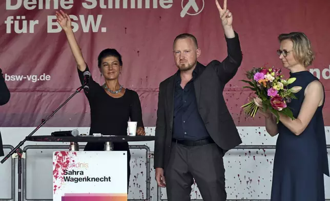 Sahra Wagenknecht, left, Chairwoman of the Sahra Wagenknecht Alliance (BSW), Katja Wolf, Thuringian BSW State Chairwoman and top candidate for the state election in Thuringia 2024, and Christian Leye, BSW General Secretary, stand together on stage after an attack with red paint at the election campaign event on Domplatz, in Erfurt, Germany, Thursday Aug. 29, 2024. (Martin Schutt/dpa via AP)