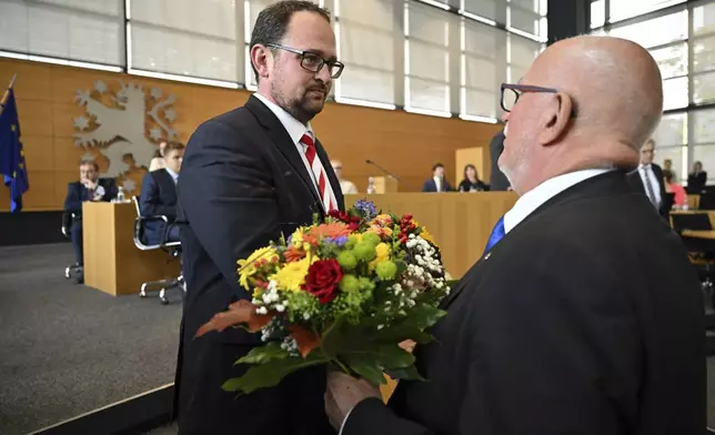 J'rgen Treutler, right, AfD member of parliament and senior president, congratulates Christian Democratic Union's Thadäus König on his election as state parliament president during the constituent session of the Thuringian state parliament in Erfurt, Germany Saturday, Sept. 28, 2024. (Martin Schutt/dpa via AP)