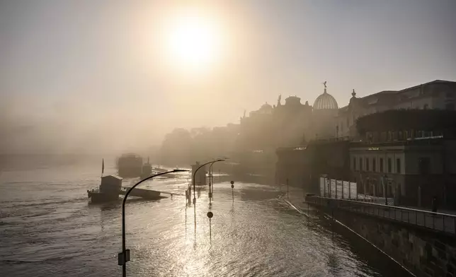 A view of the Terrassenufer in the Old Town is flooded by the high water of the Elbe in the morning fog, in Dresden, Germany, Wednesday, Sept. 18, 2024. (Robert Michael/dpa via AP)