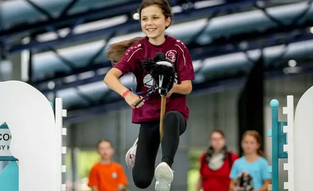 A participant clears the bar during the first German Hobby Horsing Championship in Frankfurt, Germany, Saturday, Sept. 14, 2024. (AP Photo/Michael Probst)