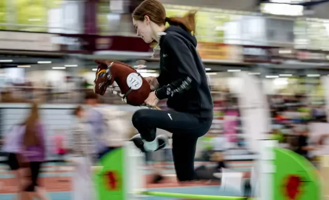 A participant clears the bar during the first German Hobby Horsing Championship in Frankfurt, Germany, Saturday, Sept. 14, 2024. (AP Photo/Michael Probst)