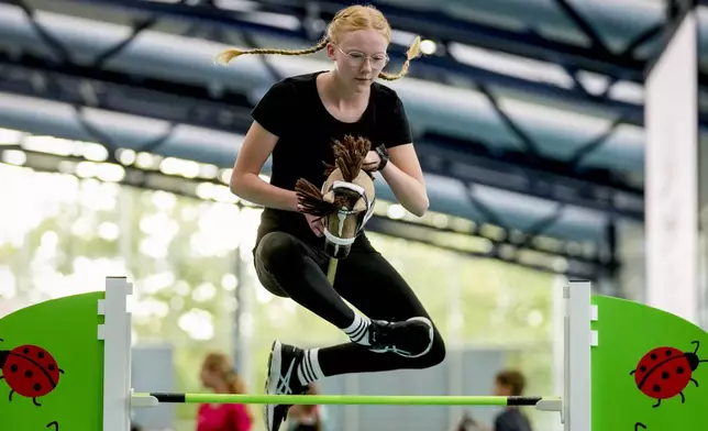 A participant clears the bar during the first German Hobby Horsing Championship in Frankfurt, Germany, Saturday, Sept. 14, 2024. (AP Photo/Michael Probst)