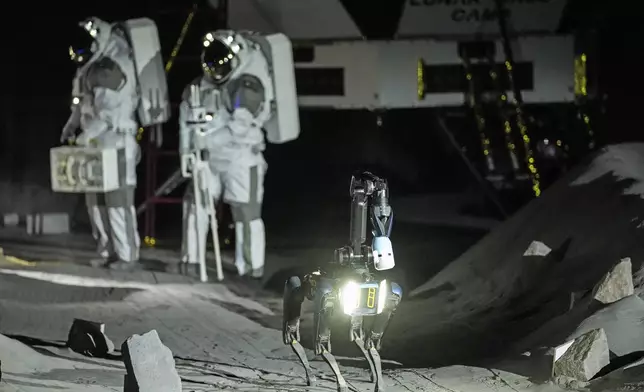 Astronauts Thomas Pesquet of France and Matthias Maurer of Germany and their canine-like robot demonstrate their training in lunar surface simulating conditions for future moon missions, like the Artemis lunar exploration program led by NASA, at the opening of the new LUNA facility at the European Astronaut Center in Cologne, Germany, Wednesday, Sept. 25, 2024. (AP Photo/Martin Meissner)