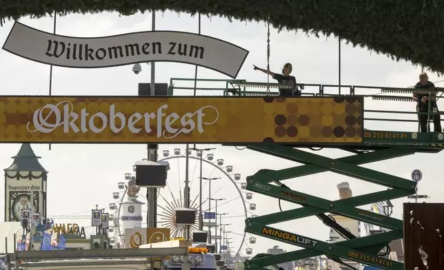 Workers stand on a lifting platform during construction work on the Oktoberfest grounds at the main entrance, in Munich, Germany, Wednesday, Sept. 18, 2024. (Peter Kneffel/dpa via AP)