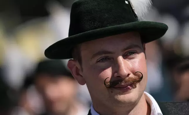 A visitor in traditional Bavarian clothes and a moustache is seen at the start of the 189th 'Oktoberfest' beer festival in Munich, Germany, Saturday, Sept. 21, 2024. (AP Photo/Matthias Schrader)