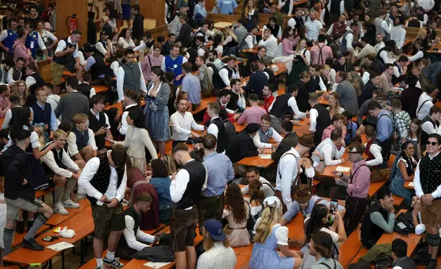 Visitors secured their place in a beer tent, awaiting the start of the 189th 'Oktoberfest' beer festival in Munich, Germany, Saturday, Sept. 21, 2024. (AP Photo/Matthias Schrader)