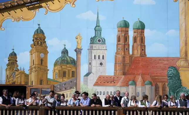 Visitors await the start of the 189th 'Oktoberfest' beer festival in front of paintings showing Munich landmarks in Munich, Germany, Saturday, Sept. 21, 2024. (AP Photo/Matthias Schrader)