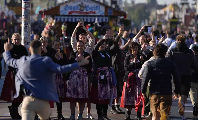 Waitresses film the opening start of the 189th 'Oktoberfest' beer festival in Munich, Germany, Saturday, Sept. 21, 2024. (AP Photo/Matthias Schrader)