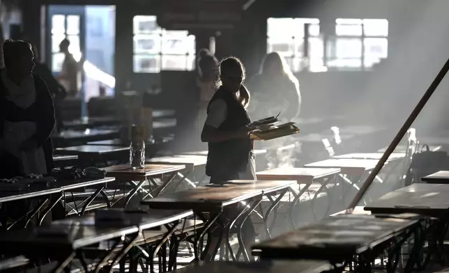 A waitress prepares tables in a marquee for the start of the 189th 'Oktoberfest' beer festival in Munich, Germany, early Saturday morning, Sept. 21, 2024. (AP Photo/Matthias Schrader)