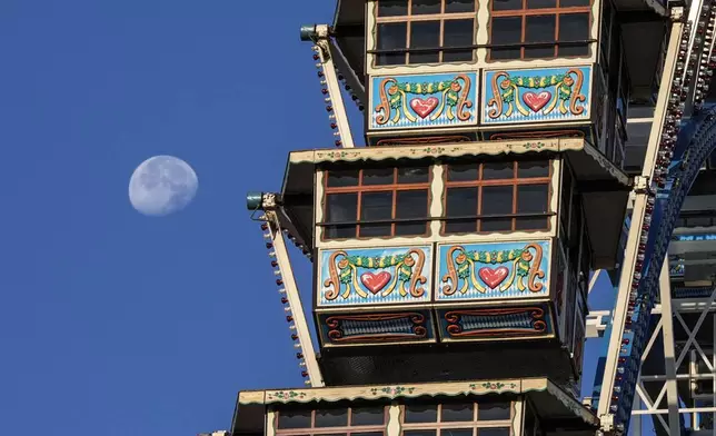 A traditional Ferris wheel waits in front of the moon for the start of the 189th 'Oktoberfest' beer festival in Munich, Germany, Saturday morning, Sept. 21, 2024. (AP Photo/Matthias Schrader)