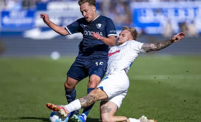 Bochum's Felix Passlack, left, and Kiel's Tymoteusz Puchacz, right, challenge for the ball during the German Bundesliga soccer match between VfL Bochum and Holstein Kiel in Bochum, Germany, Saturday, Sept. 21, 2024. (David Inderlied/dpa via AP)