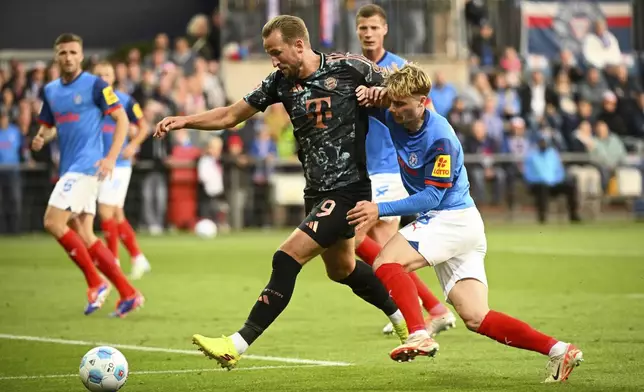 Bayern's Harry Kane, left, holds back Kiel's Finn Porath during the German Bundesliga soccer match between Holstein Kiel and Bayern Munich, at the Holsten stadium in Kiel, Germany, Saturday, Sept. 14, 2024. (Gregor Fischer/dpa via AP)