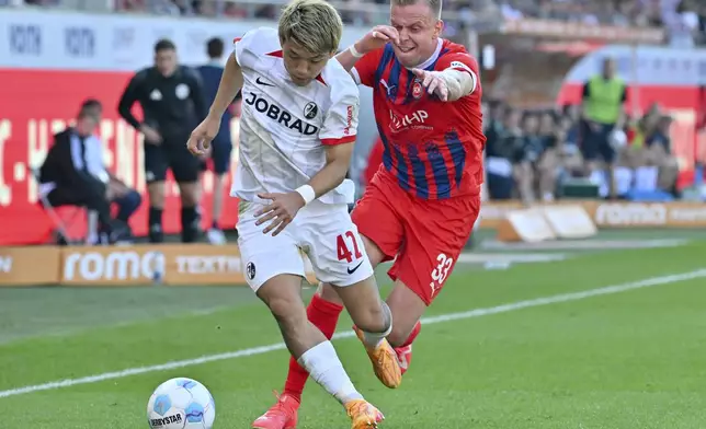 SC Freiburg's Ritsu Doan, left, and Heidenheim's Lennard Maloney, right, in action during the Bundesliga soccer match between FC Heidenheim 1846 and SC Freiburg in Heidenheim, Germany, Saturday Sept. 21, 2024. (Jan-Philipp Strobel/dpa via AP)