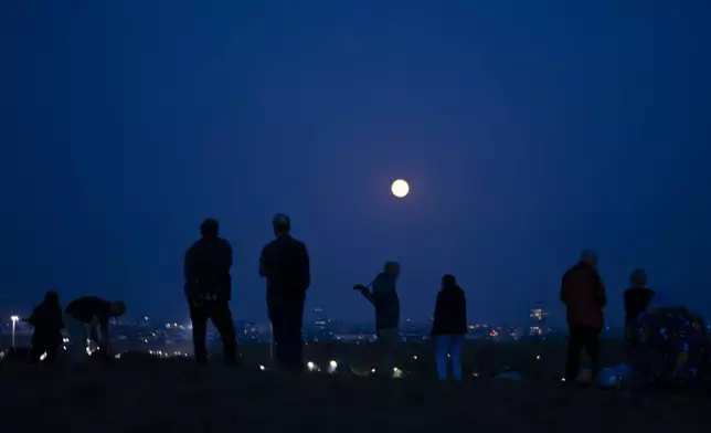 People spot the full Harvest moon at the Teufelsberg, Devils Hill, in Berlin, Germany, Tuesday, Sept. 17, 2024. (AP Photo/Markus Schreiber)