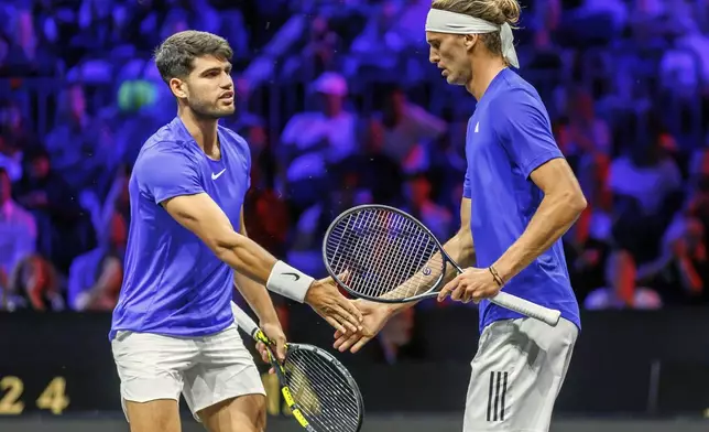 Team Europe's Carlos Alcaraz, left, and Alexander Zverev slap hands during a doubles match against Team World's Ben Shelton and Taylor Fritz on the first day of the Laver Cup tennis tournament at the Uber arena in Berlin, Germany, Friday, Sept. 20, 2024. (Andreas Gora/dpa via AP)