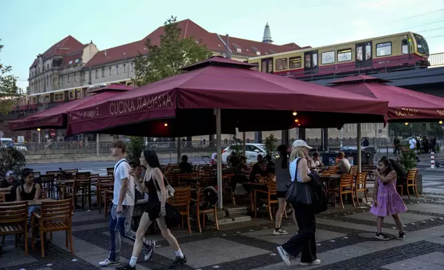 People eat doner in the outdoor area of a doner kebab restaurant in Berlin, Germany, Wednesday, Sept. 18, 2024. (AP Photo/Ebrahim Noroozi)