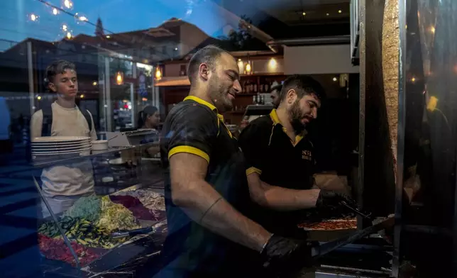 Turkish doner cooks prepare doner kebabs for customers in a doner kebab restaurant in Berlin, Germany, Wednesday, Sept. 18, 2024. (AP Photo/Ebrahim Noroozi)