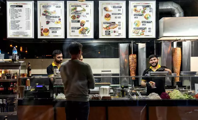 Turkish doner cooks prepare doner kebabs for customers in a doner kebab restaurant in Berlin, Germany, Wednesday, Sept. 18, 2024. (AP Photo/Ebrahim Noroozi)