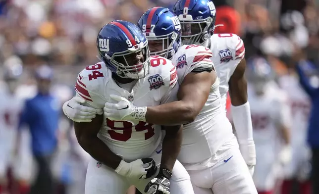 New York Giants defensive tackle Elijah Chatman (94) is congratulated by defensive tackle Dexter Lawrence II, middle, and linebacker Brian Burns after sacking Cleveland Browns quarterback Deshaun Watson during the first half of an NFL football game, Sunday, Sept. 22, 2024 in Cleveland. (AP Photo/Sue Ogrocki)