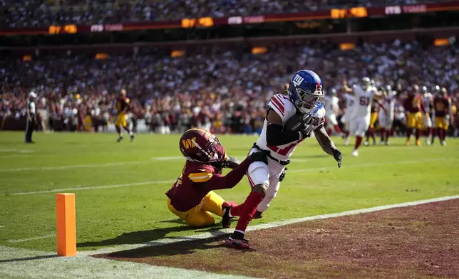 New York Giants wide receiver Wan'Dale Robinson, right, runs into the end zone for a touchdown as Washington Commanders cornerback Mike Sainristil, left, defends during the second half of an NFL football game in Landover, Md., Sunday, Sept. 15, 2024. (AP Photo/Matt Slocum)