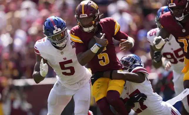 Washington Commanders quarterback Jayden Daniels (5) is tackled by New York Giants safety Jason Pinnock (27) during the first half of an NFL football game in Landover, Md., Sunday, Sept. 15, 2024. (AP Photo/Matt Slocum)