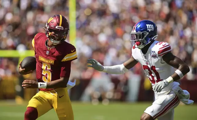 Washington Commanders quarterback Jayden Daniels (5) runs past New York Giants safety Tyler Nubin (31) during the first half of an NFL football game in Landover, Md., Sunday, Sept. 15, 2024. (AP Photo/Steve Ruark)