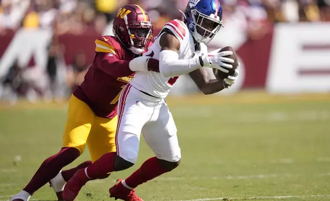 New York Giants wide receiver Malik Nabers, right, stretches for a first down as he is tackled by Washington Commanders cornerback Noah Igbinoghene, left, during the second half of an NFL football game in Landover, Md., Sunday, Sept. 15, 2024. (AP Photo/Matt Slocum)